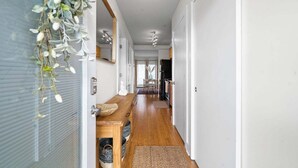 A narrow hallway with a wooden bench, a woven rug, and a hanging plant. - Loft #210 (540 N 2nd St) (Fredericton)