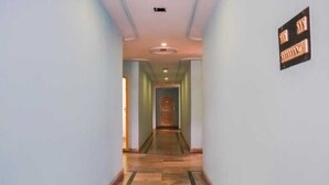 Un couloir doté d’un plancher en bois, de murs aux couleurs claires et d’une porte au fond.