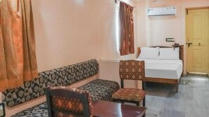 Une pièce comprenant un lit, un canapé et une chaise. Un appareil de climatisation est fixé au mur.