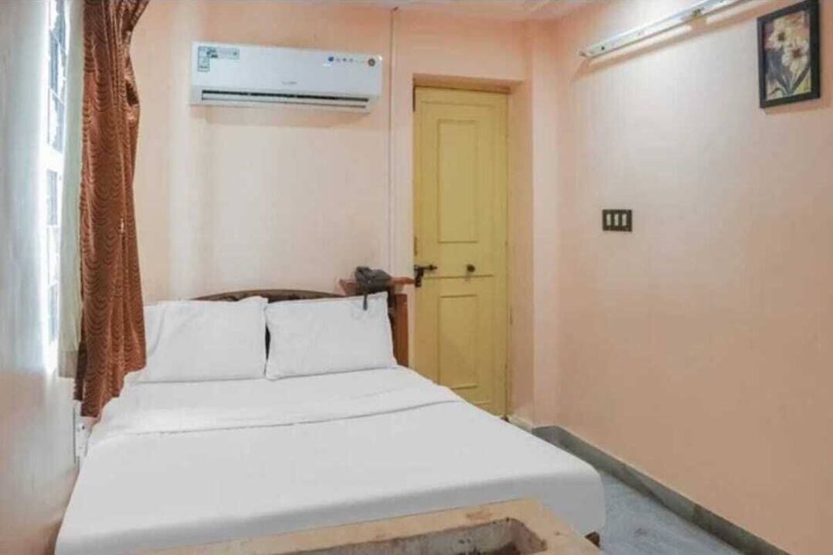 Un dormitorio con cama, unidad de aire acondicionado, puerta y lámpara.