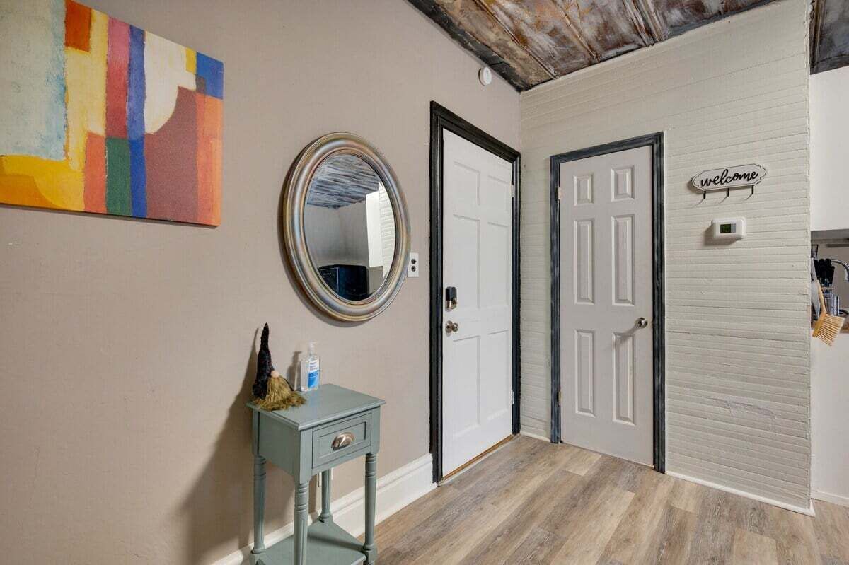 A hallway with a round mirror, a door, and a welcome sign.