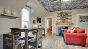 A loft-style room with a dining area, a red sofa, and a fireplace. - Unit #4 117 Marion St (Clarksville)