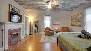 A bedroom with a fireplace, a bed, a ceiling fan, and a painting on the wall. - Unit #4 117 Marion St (Clarksville)