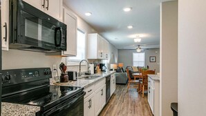 A modern kitchen with a black stove, white cabinets, and a microwave.