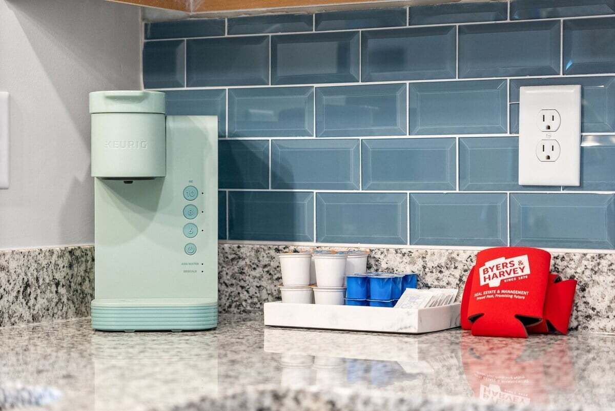 A kitchen with a Keurig coffee maker, a coffee machine, and a BYERS & HARVEY bag on the counter.