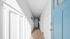 Un pasillo con puertas blancas a un lado y una puerta azul al otro.