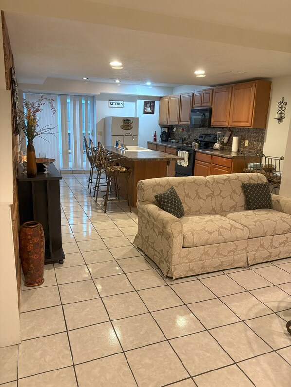 A modern kitchen with wooden cabinets, a central island, and a dining area with chairs.