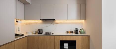 A modern kitchen with wooden cabinets, a marble countertop, and built-in appliances.
