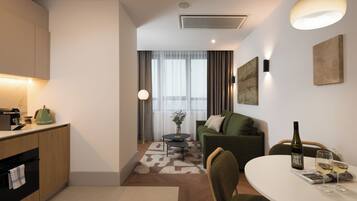 A modern hotel room with a kitchenette, a dining area, and a living space.