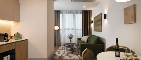 A modern hotel room with a kitchenette, a dining area, and a living space.