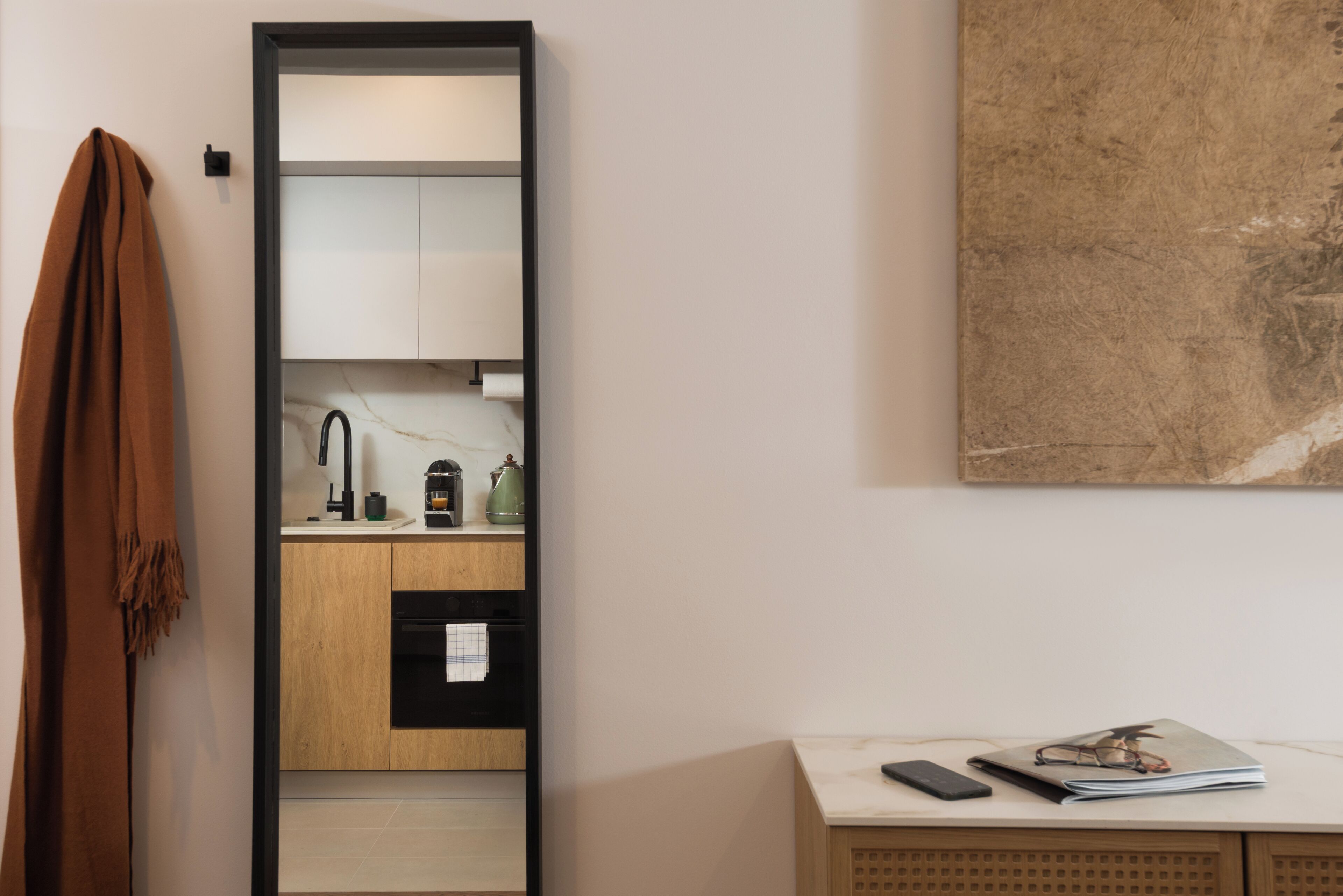 A modern kitchen with wooden cabinets, a black countertop, and a hanging towel.