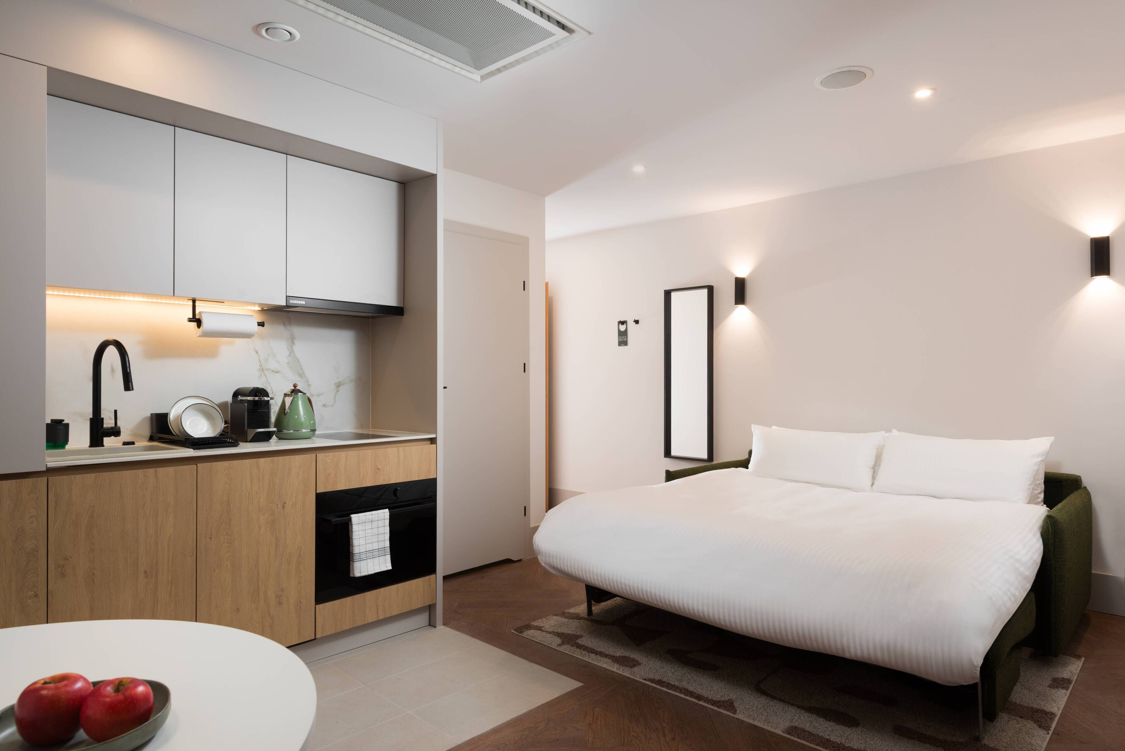 Une chambre d’hôtel moderne équipée d’un lit, d’une petite kitchenette et d’une salle de bain.