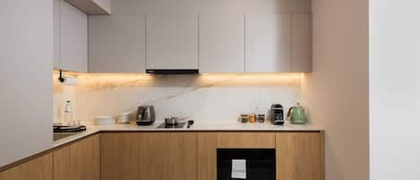 A modern kitchen with wooden cabinets, a marble countertop, and built-in appliances.