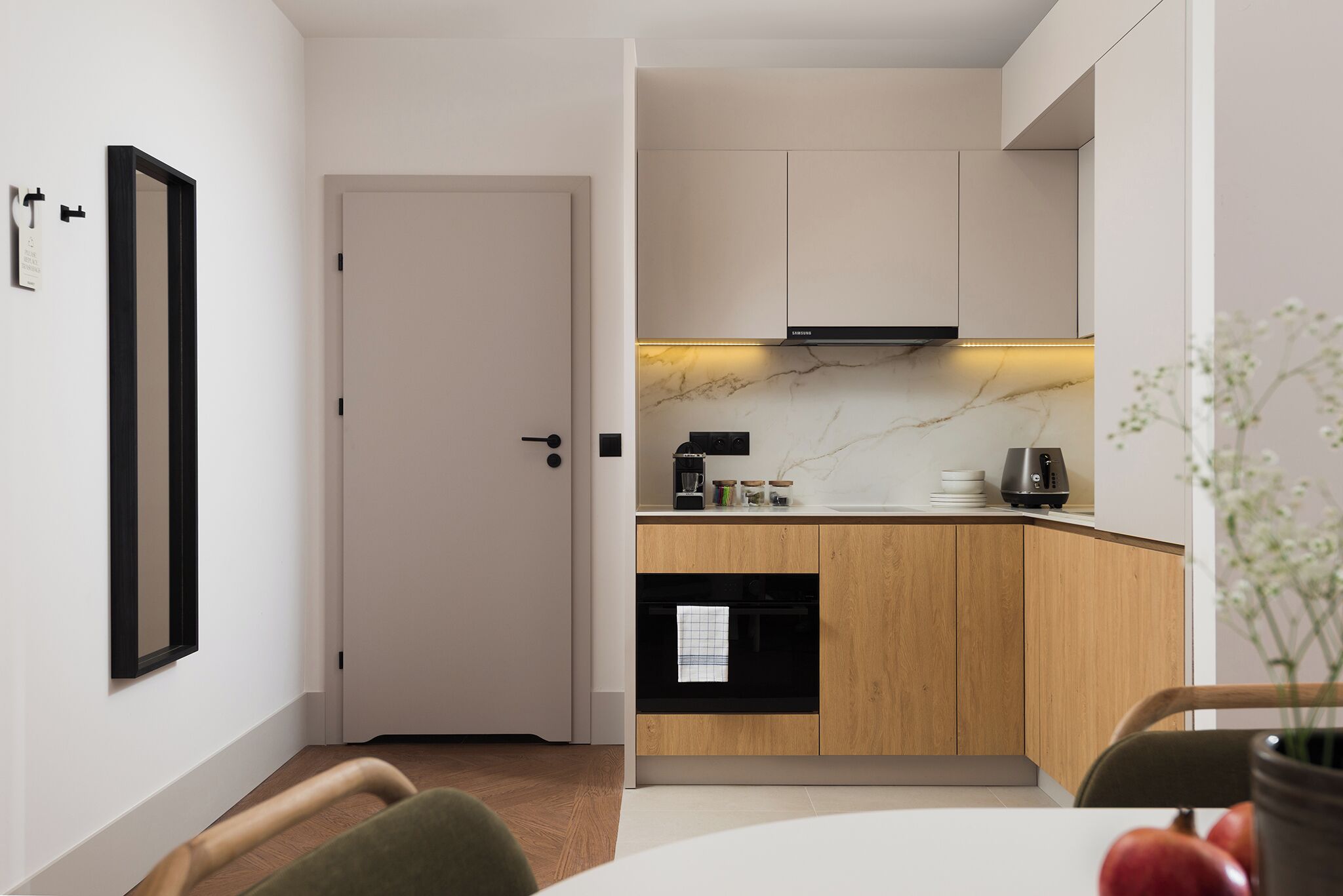 Una cocina moderna con armarios de madera, horno negro y encimera de mármol.