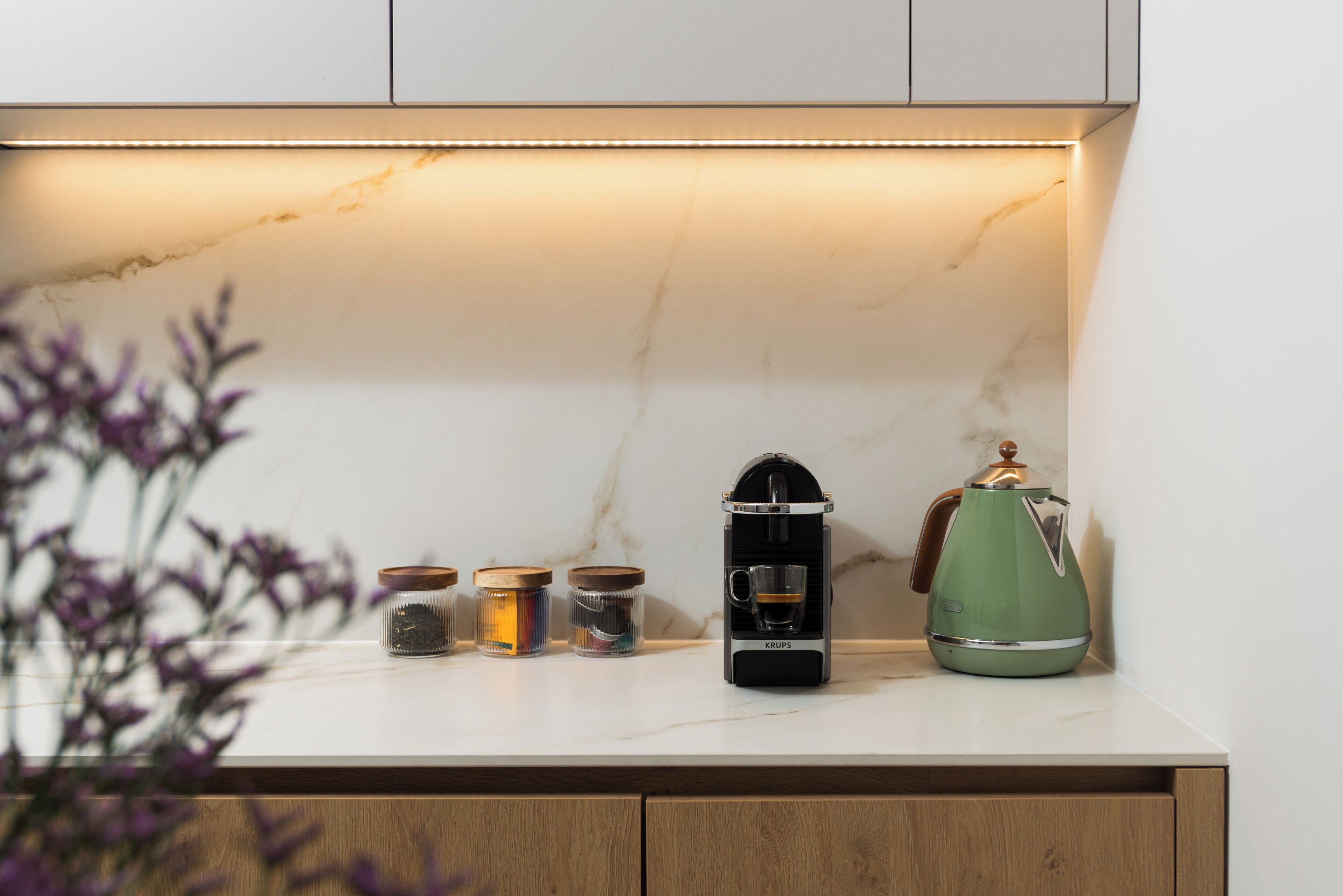 A kitchen counter with a coffee maker, a kettle, and jars of spices.