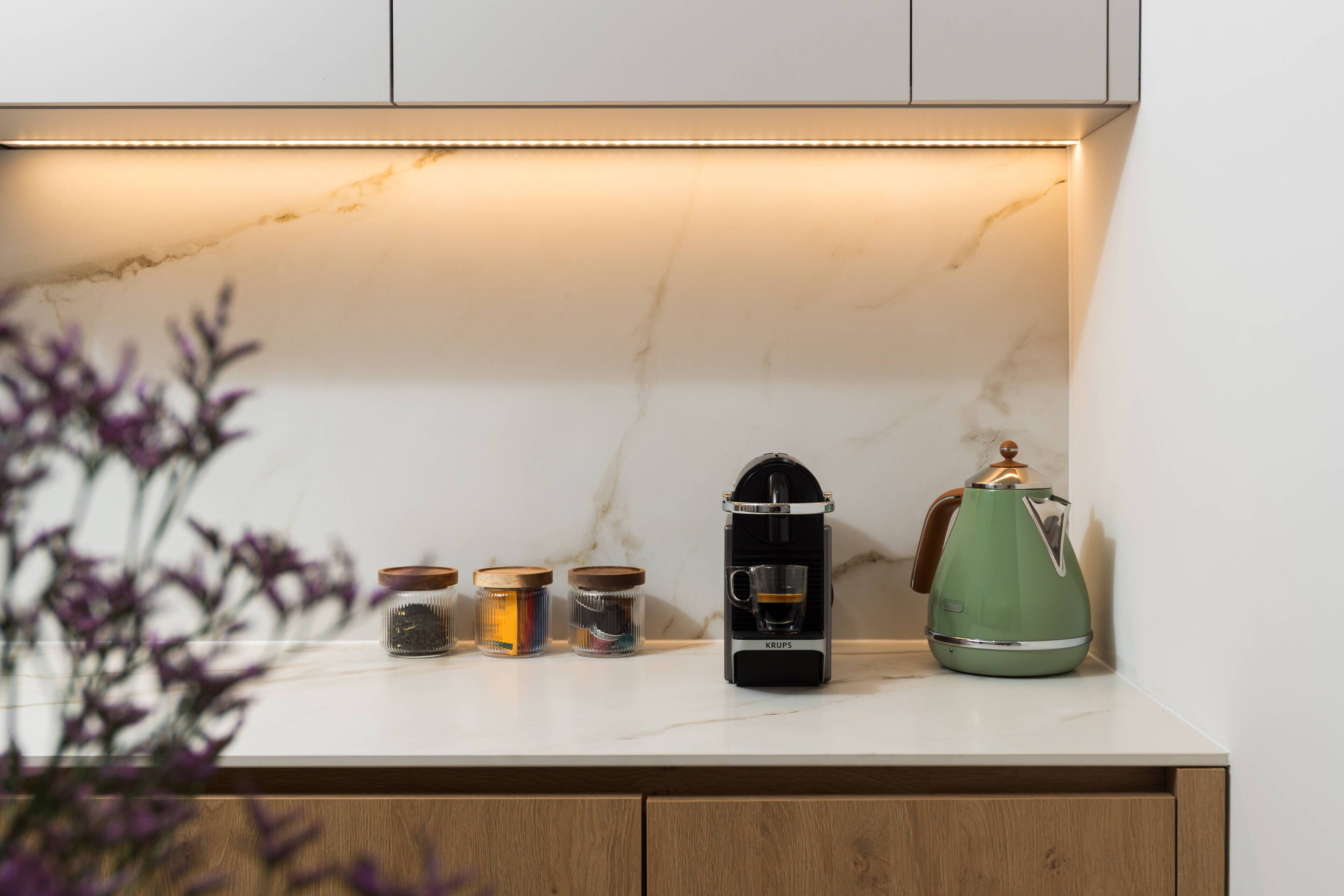 Una encimera de cocina con una cafetera, un hervidor y frascos de especias.