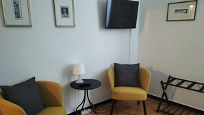 A room with two yellow armchairs, a small table with a lamp, and a flat-screen TV mounted on the wall. - Gianlu' Cosy Apartment with A/C (Monterosso al Mare)