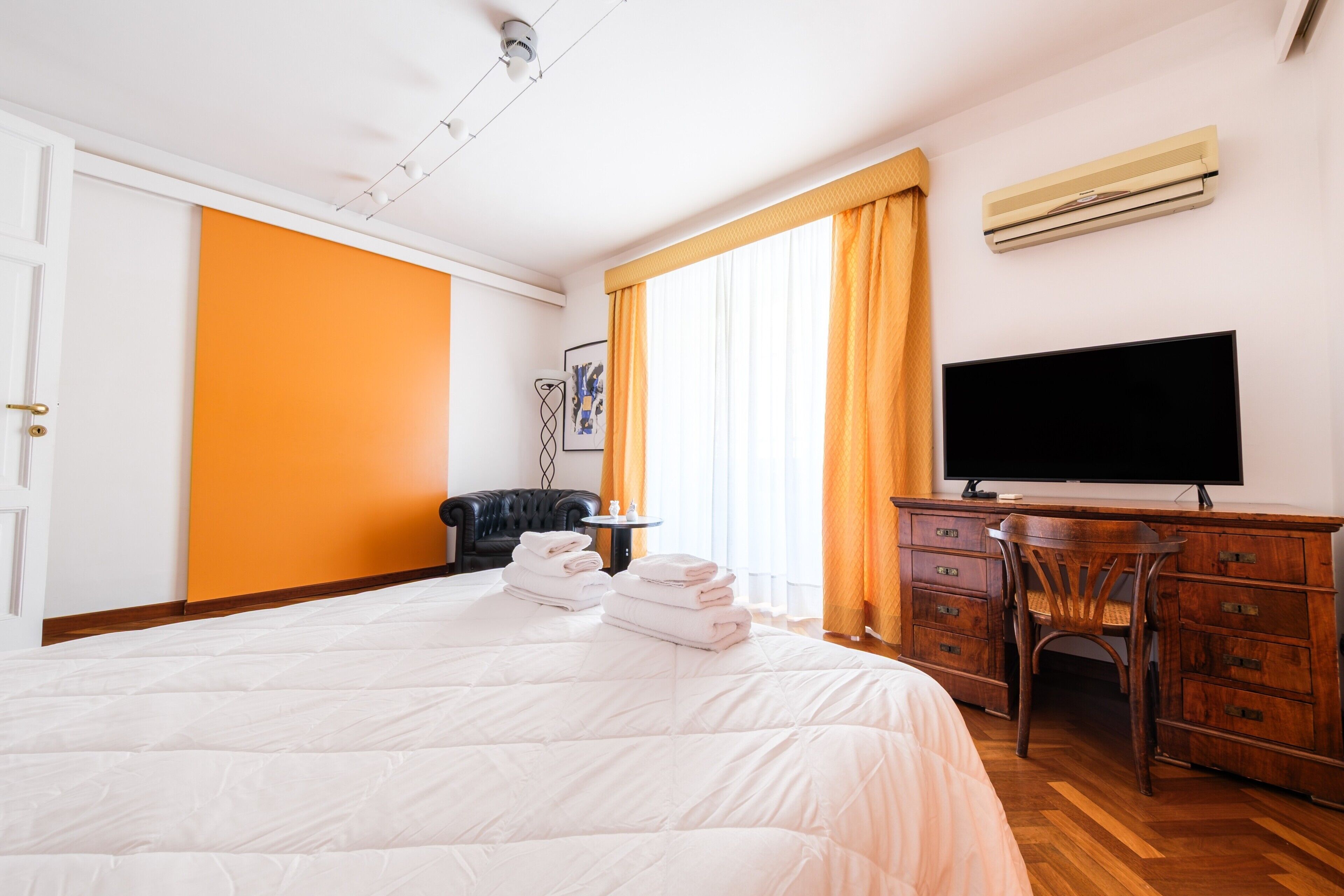 Een hotelkamer met een bed, een bureau, een televisie en een airconditioning.