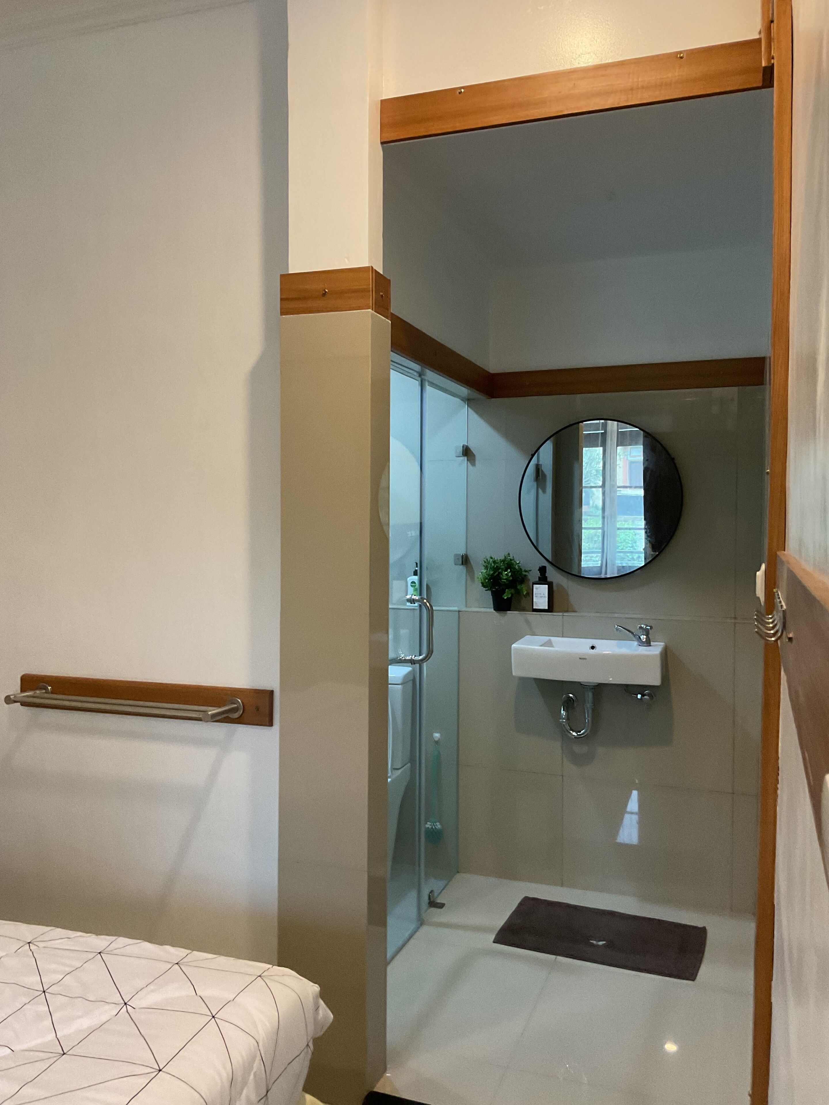 Un baño con cabina de ducha de vidrio, lavamanos y espejo.