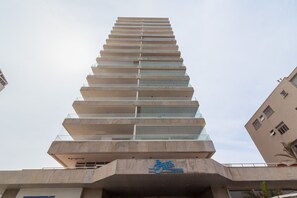 Un edificio de gran altura con diseño arquitectónico moderno, que cuenta con varios balcones y una señalización destacada que indica que es una propiedad residencial.
