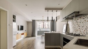 A modern kitchen with a central island, built-in appliances, and pendant lighting. - Book and Bed-Jingan Temple (Shanghai)