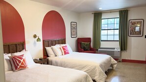 A hotel room with two beds, a red arch wall, a window with green curtains, and a ceiling light fixture.