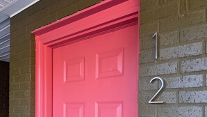 A red door with a number '1' on a brick wall.