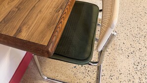 A wooden dining table with green cushioned chairs.