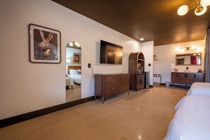 Habitación de hotel con una cama grande, un tocador, un televisor y un espejo.