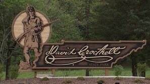 A sign for David Crockett State Park with a prominent figure holding a rifle.