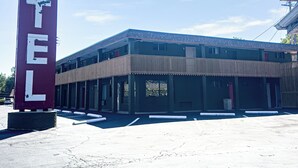 Un motel con un letrero grande, varias habitaciones y un estacionamiento.