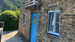 A stone building with a blue door and windows, a wooden balcony, and a stone pathway. - Casas do Sinhel (Góis)