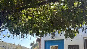 A stone patio with a blue door, a table with chairs, and a sign reading "Casa Relva da Mo". - Casas do Sinhel (Góis)