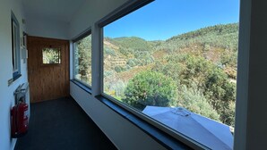 A hallway with a large window offering a view of a hilly landscape. - Casas do Sinhel (Góis)