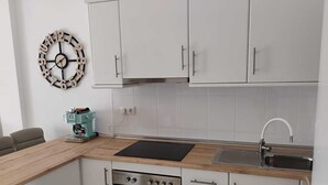 Una cocina moderna con armarios blancos, horno empotrado, cafetera y un reloj de pared.