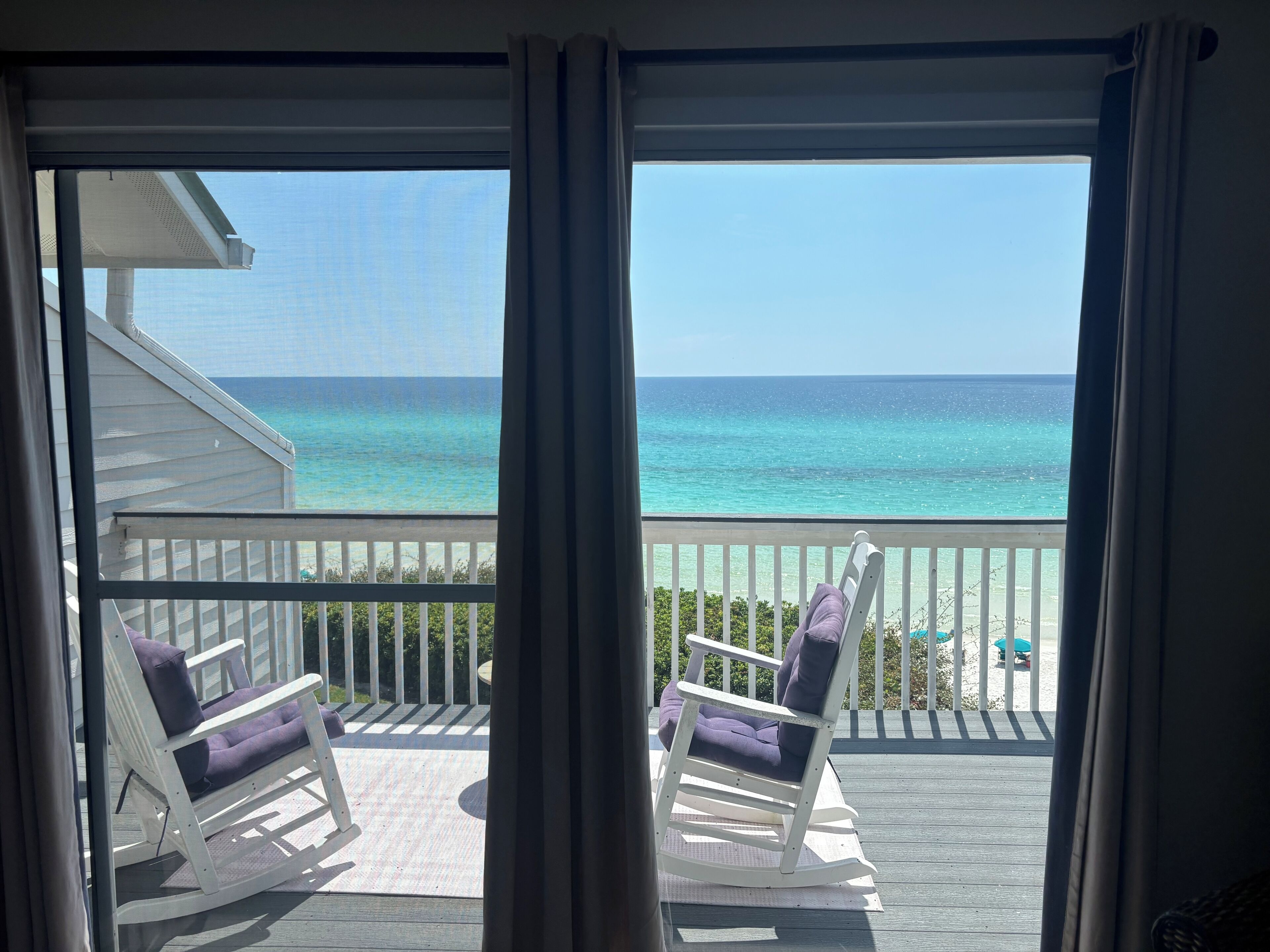 Un balcon avec deux fauteuils à bascule donnant sur une vue dégagée sur l’océan.
