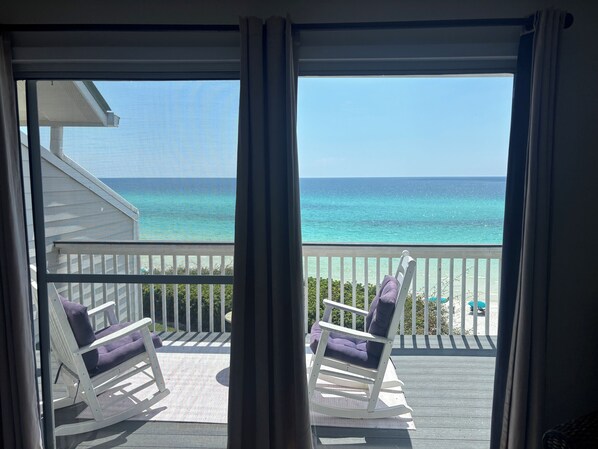 A balcony with two rocking chairs facing a clear view of the ocean.
