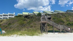 Une propriété située en bord de mer, avec un escalier en bois menant à un bâtiment doté de toits végétalisés.
