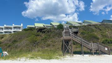 A beachfront property with a wooden staircase leading to a building with green roofs.