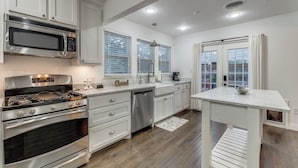 Una cocina moderna con electrodomésticos de acero inoxidable, armarios blancos y una isla central.