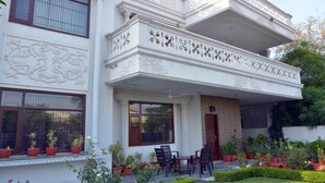 Un edificio a due piani con dettagli architettonici elaborati, un balcone con posti a sedere e piante in vaso intorno all'ingresso.