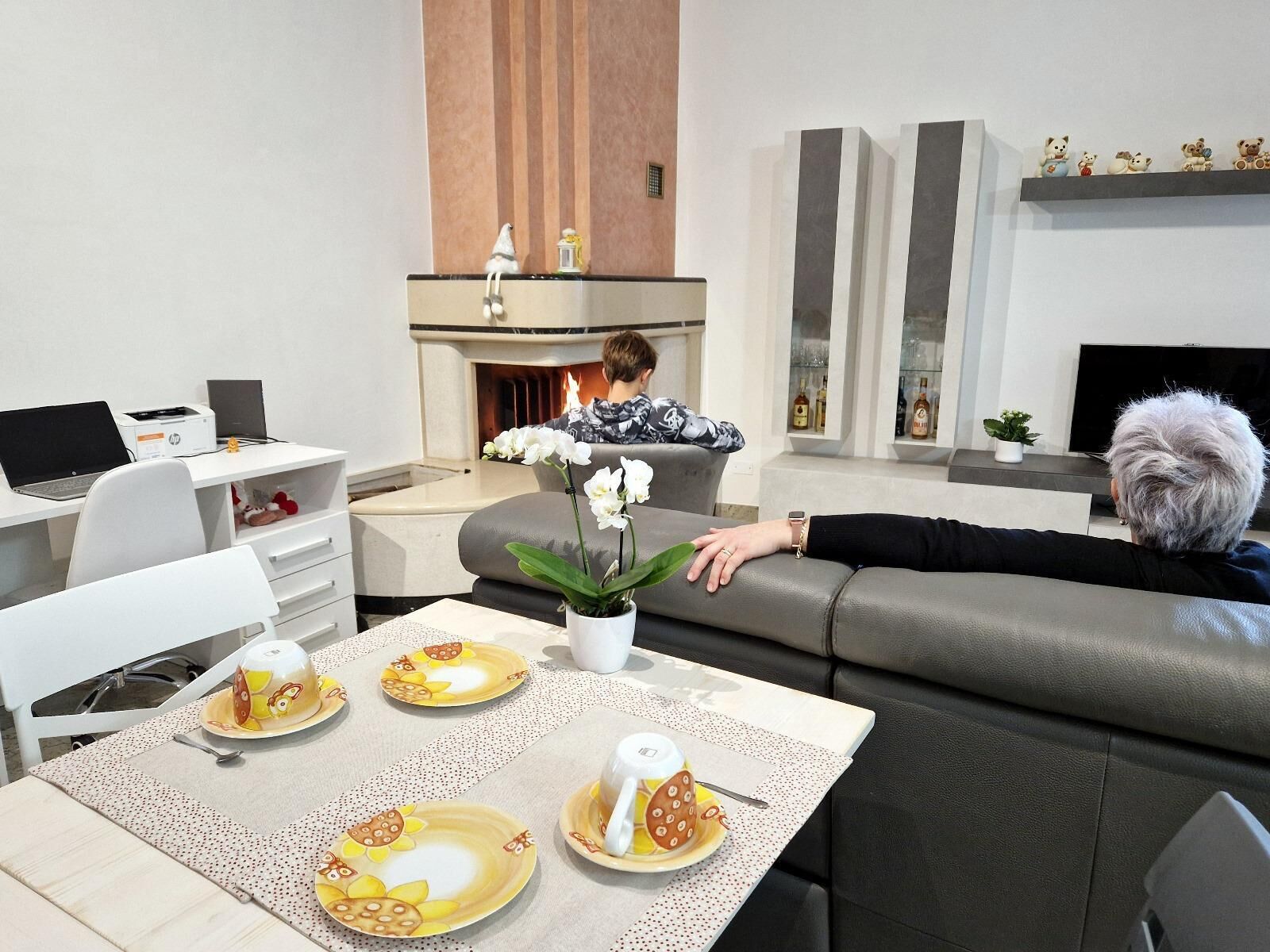 Ein modernes Wohnzimmer mit Kamin, einer Essecke mit Tisch für zwei Personen und einem Sofa.