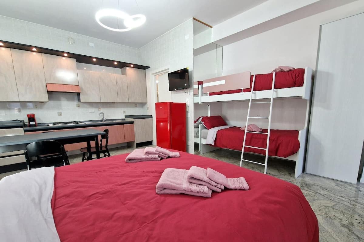 A compact room with a bunk bed, a desk, and a kitchenette.