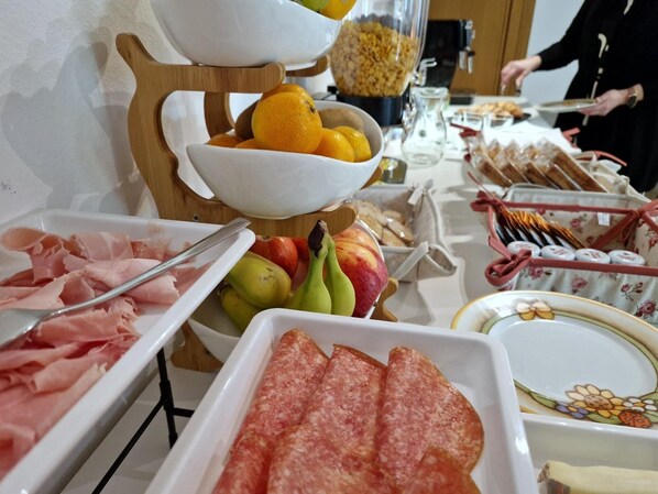 A buffet setup with various food items including fruits, meats, and bread. - iris b&b (Montorio)
