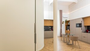 Eine moderne Küche mit Holzschränken, einem Glastisch und einer Mikrowelle.