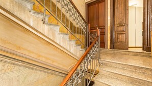 Eine prächtige Treppe mit aufwendiger Metallreling und einem Holzgeländer, die zu einer Holztür führt.