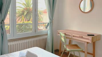 A hotel room with a bed, a desk, a chair, a television, and a window with curtains.