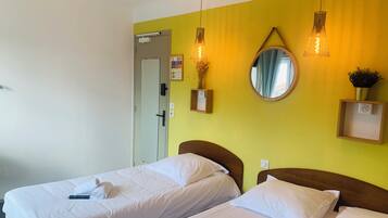 Une chambre d’hôtel avec deux lits, un ventilateur de plafond, un miroir et des lampes fixées au mur.