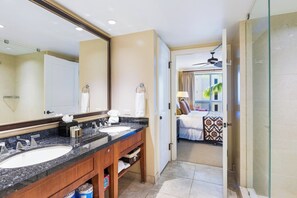 Un baño de hotel con lavamanos dobles, un espejo grande y una zona de ducha.