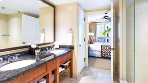 Une salle de bain d’hôtel avec deux lavabos, un grand miroir et un espace douche.